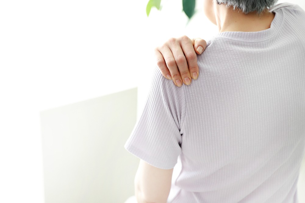여성이 뻐근한 어깨를 잡고 있는 뒷모습